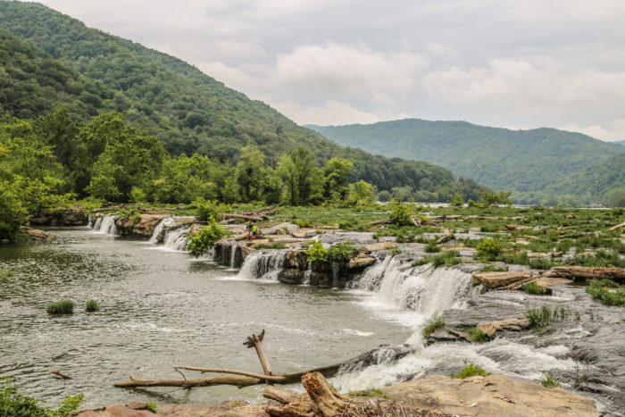 Sandstone Falls along the New River surrounded by tall green mountains and lush trees